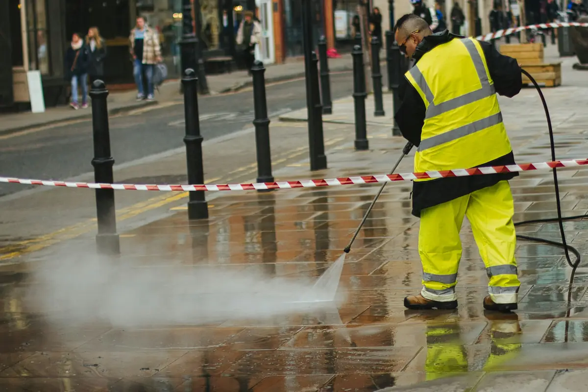 Worker pressure washing pavement